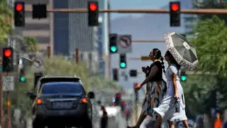 Heat ripples engulf two ladies while crossing the street in central Phoenix, Arizona