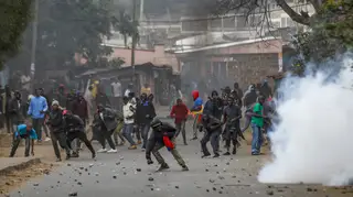Protesters throw rocks at police during clashes next to a cloud of teargas in the Kibera area of Nairobi