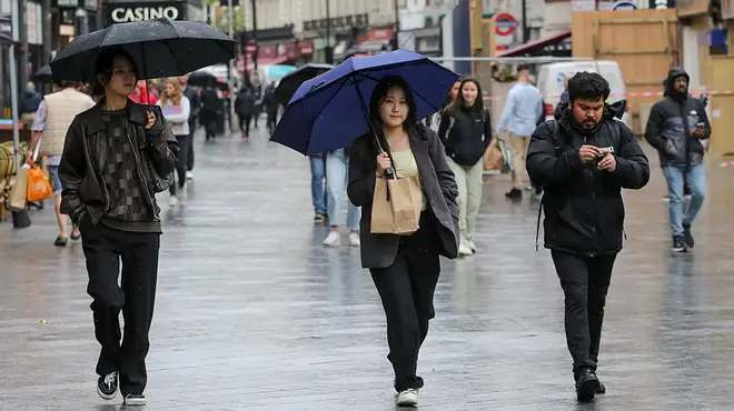 People walking around London in the rain with umbrellas.