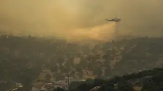 A firefighting helicopter dumps water in Mandra, west of Athens