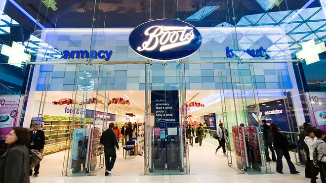 The front of a Boots store in London with people walking in and out of it