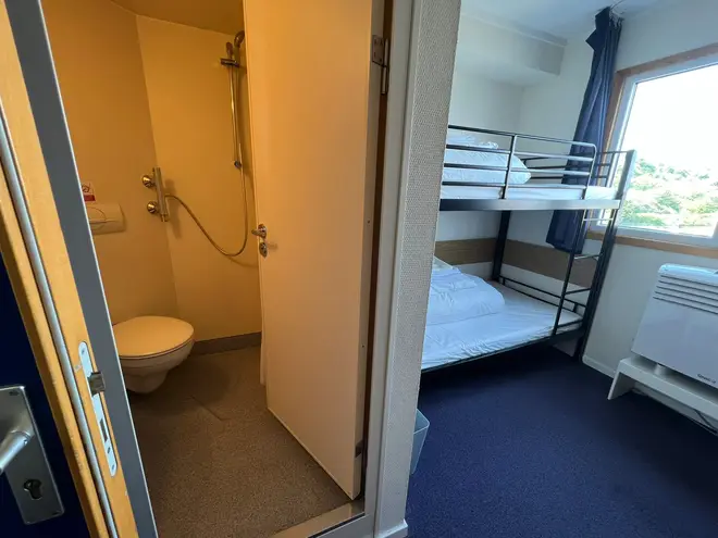 The bedroom shows a single-sized bunk bed, en-suite bathroom and a desk with a chair.
