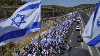 Israeli flags as people walk along the road