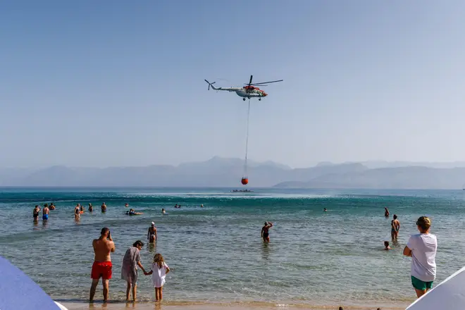 A helicopter scoops water from Agios Spiridon Beach on Corfu before dropping it onto the nearby wildfires