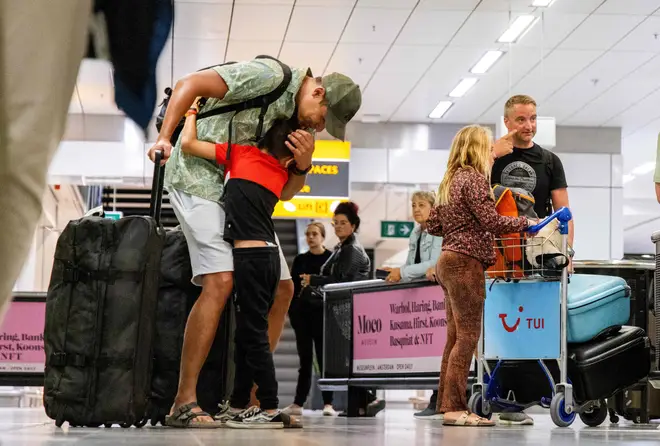 Travelers gesture as they arrive after returning from the Greek island of Rhodes where evacuations are underway due to wildfires