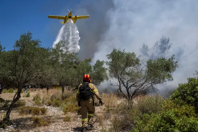 A plane dumps water on scrubland in efforts to halt the spread of the flames