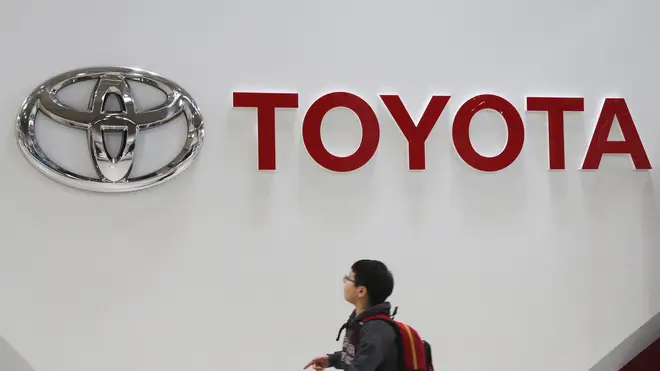 Toyota logo with man walking in front of it