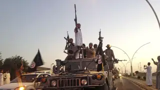 Fighters from the Islamic State group parade in a commandeered Iraqi security forces armored vehicle in the northern city of Mosul, Iraq, in June 2014