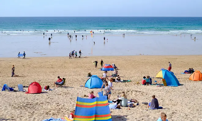 Sunny UK beach with people sunbathing and enjoying the sea