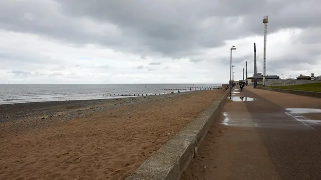 A empty and wet UK beach with overcast clouds