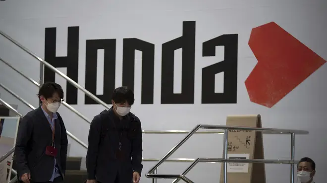People walk near the logo of Honda Motor Company at a showroom in Tokyo