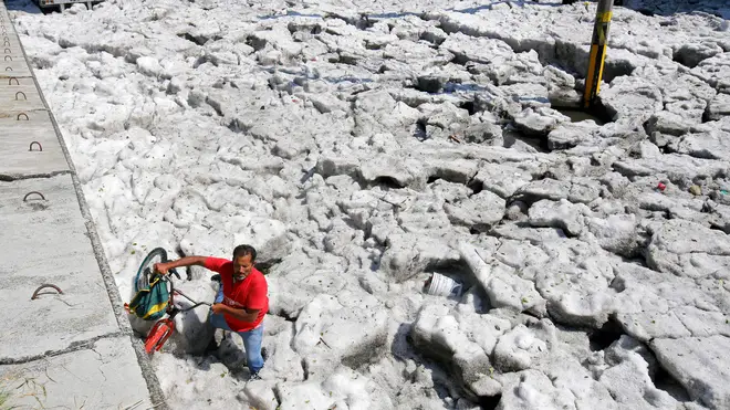 A man with a bike walks on hail in Guadalajara