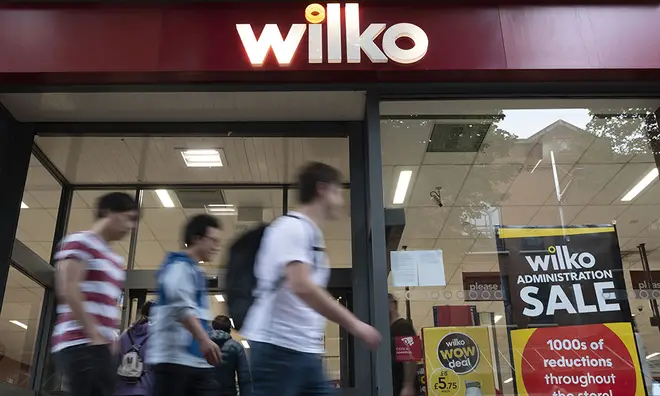 People walking past a Wilko with administration sale signs in the window