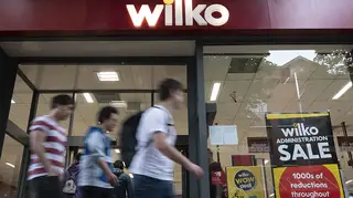 People walking past a Wilko with administration sale signs in the window