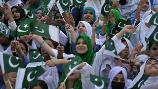 Students wave national flags to commemorate Pakistan's Independence Day