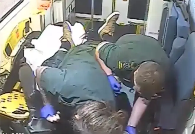 The two ambulance workers struggle to restrain the violent man.