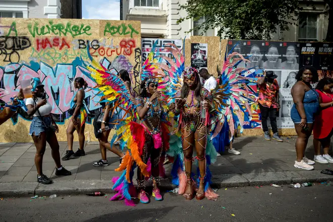 Performers in costume pause during a parade on the final day of Notting Hill Carnival