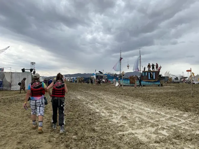Festival-goers walk through the mud at Burning Man festival