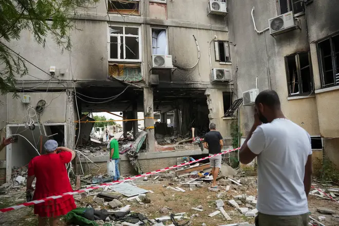 Israelis inspect a damaged residential building after it was hit by a rocket fired from the Gaza Strip, in Ashkelon, Israel