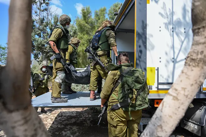 Soldiers load body bags into a truck at the site of the 'massacre' at Kfar Aza