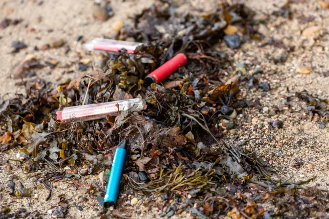 Single use disposable vapes lying discarded on a beach