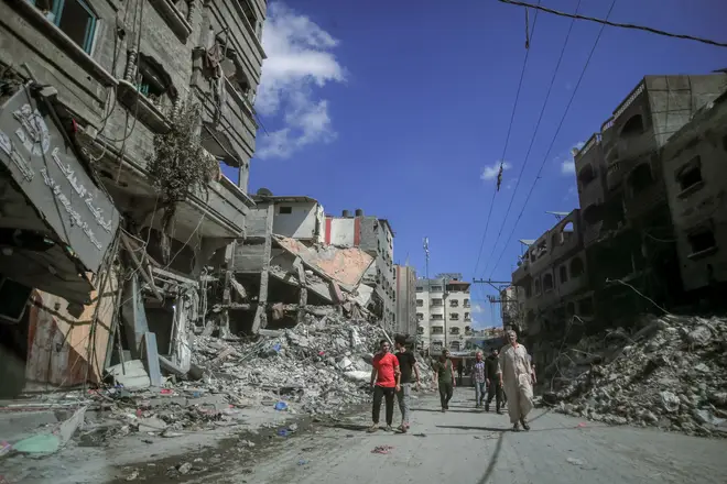 People walking amidst the destruction of houses and streets in Khan Yunis, located in the southern Gaza Strip