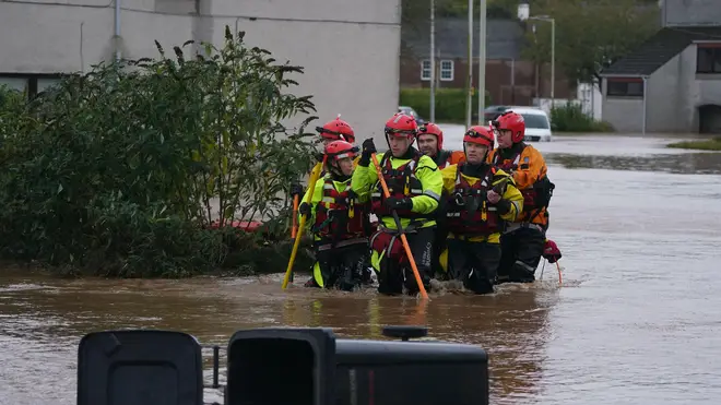 Emergency service workers walk through flood water in Brechin