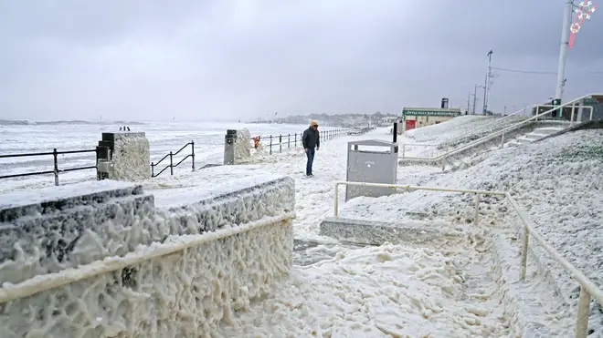 A man walks through sea foam in Seaburn, Sunderland