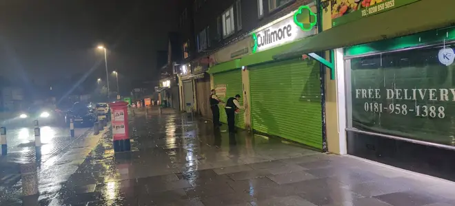 The officers are seen taking off the posters at Cullmore pharmacy in Edgware