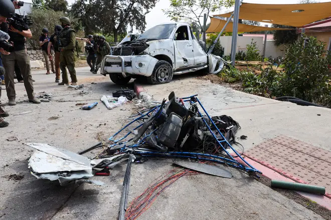 Israeli soldiers and journalists gather around a damaged powered paraglider allegedly used by Palestinian militants in Kfar Aza