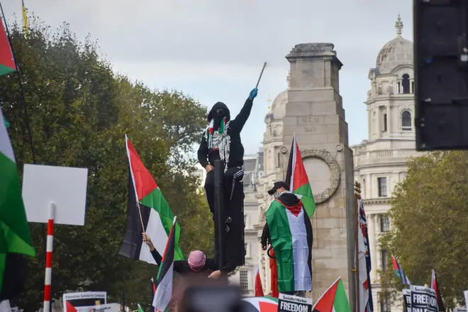 A pro-Palestinian protester climbs on a traffic light and sets off fireworks near The Cenotaph in Whitehall