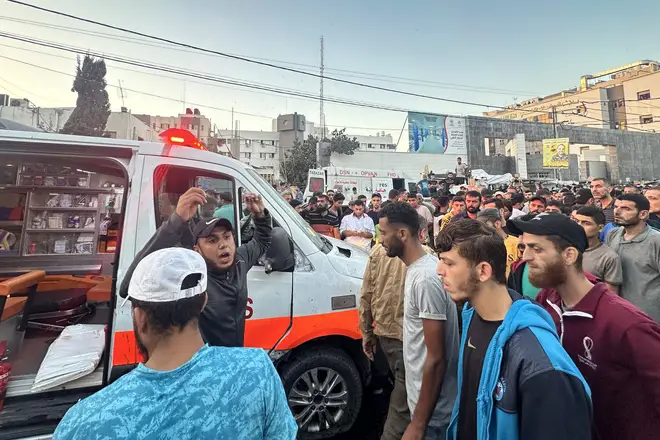 People gather around an ambulance damaged in an Israeli strike