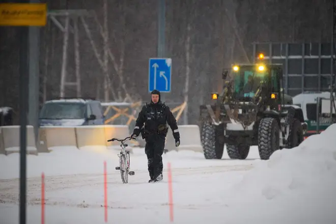 A border guard moves a bicycle of an asylum seeker at the Vartius border station in Kuhmo, Eastern Finland