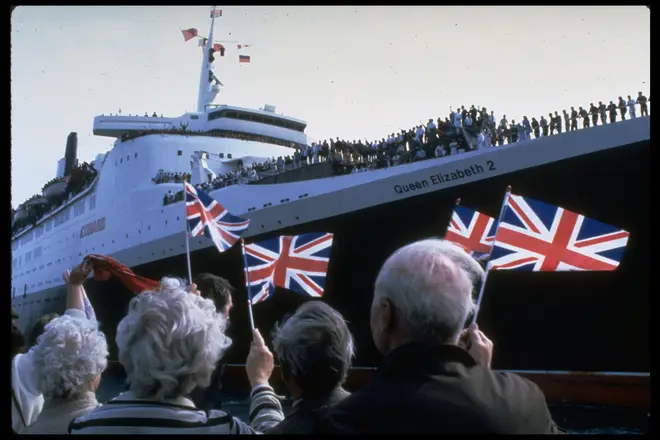 Wellwishers waving British flags as they bid farewell to troops sailing on QE2 as it departs for Falkland Islands