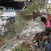 People sit near the site of the tunnel that has collapsed