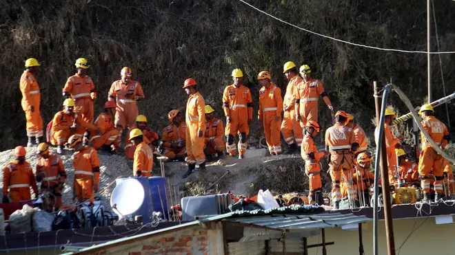 Rescuers rest at the site of the collapsed tunnel