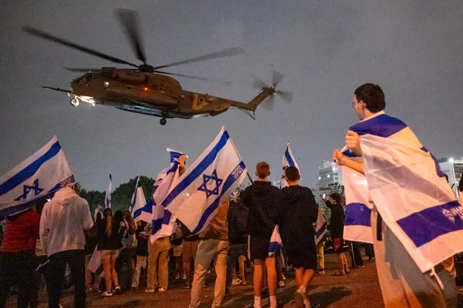 People wave flags and cheer as a second helicopter with Israeli hostages released earlier by Hamas lands at Schneider medical centre on the third day of the temporary truce