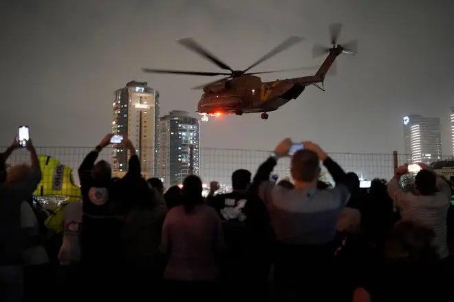 A group of Israelis watch as a helicopter carrying hostages released from the Gaza Strip lands at the helipad of the Schneider Children's Medical Center in Petah Tikva, Israel, Sunday Nov. 26,