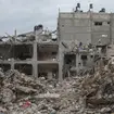 Palestinians walk by a destroyed building in Jebaliya refugee camp, Gaza Strip