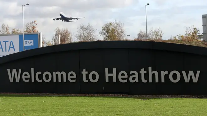 A plane flies over a 'Welcome to Heathrow' sign