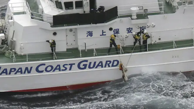Japanese coastguard members pick up a floating object as they conduct search and rescue operation in the waters off Yakushima Island, Kagoshima prefecture, southern Japan on Thursday