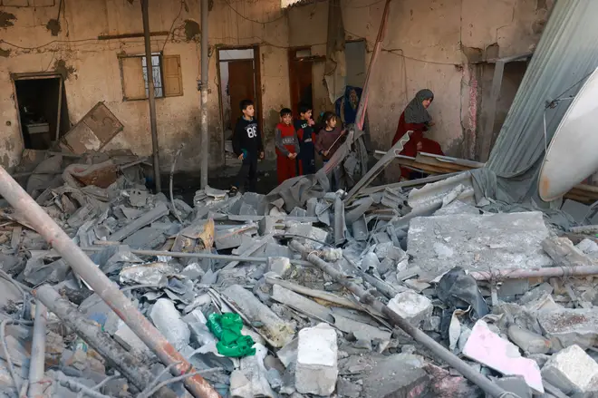 Palestinians inspect the damage in the rubble of a building destroyed during Israeli bombardment in Rafah