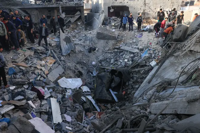 People gather around a crater among destroyed buildings in the aftermath of an overnight Israeli bombing on Sunday