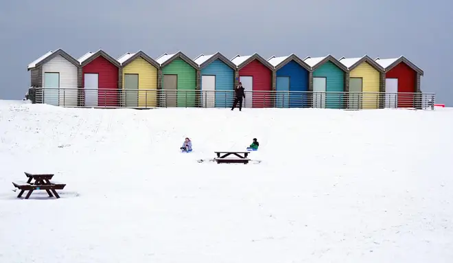 People ride sledges besides the beach huts at Blyth in Northumberland