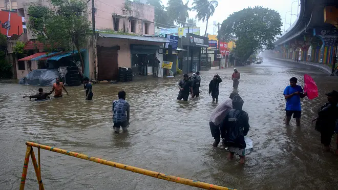 People wade through a flooded street in Chennai