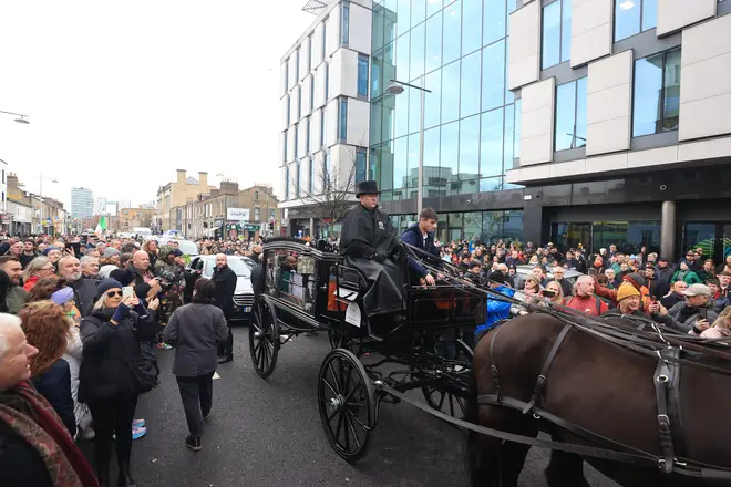 A huge crowd gathers around the funeral cortege