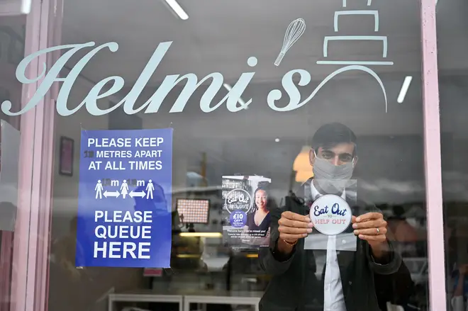 Rishi Sunak places an Eat Out to Help Out sticker in the window of a business during a visit to Rothesay on the Isle of Bute, Scotland.
