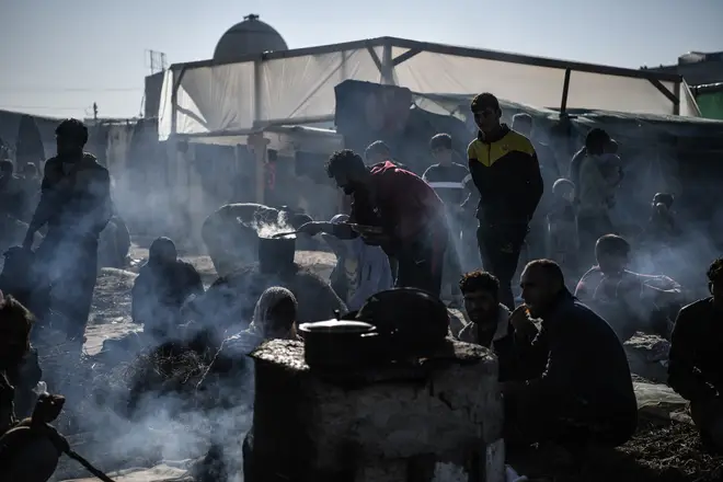 Palestinians prepare food in a clay oven they built themselves, displaced to Southern Gaza due to the ongoing war