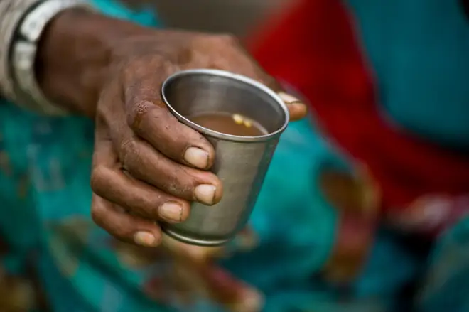 A woman holding a metal cup of masala chai