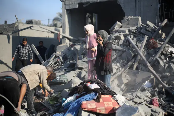 Palestinians react as they stand on the rubble of their home after an Israeli strike in Khan Younis